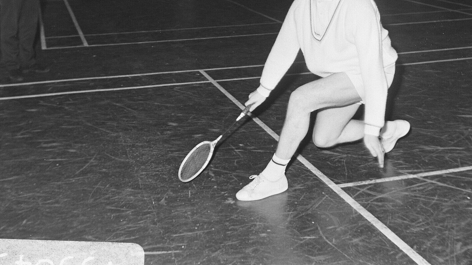 Une personne qui joue au badminton s’agenouille très bas sur le terrain et étire sa raquette vers le sol pour atteindre un volant bien sous la hauteur du corps, le type de point de contact difficile que ce guide diagnostique.